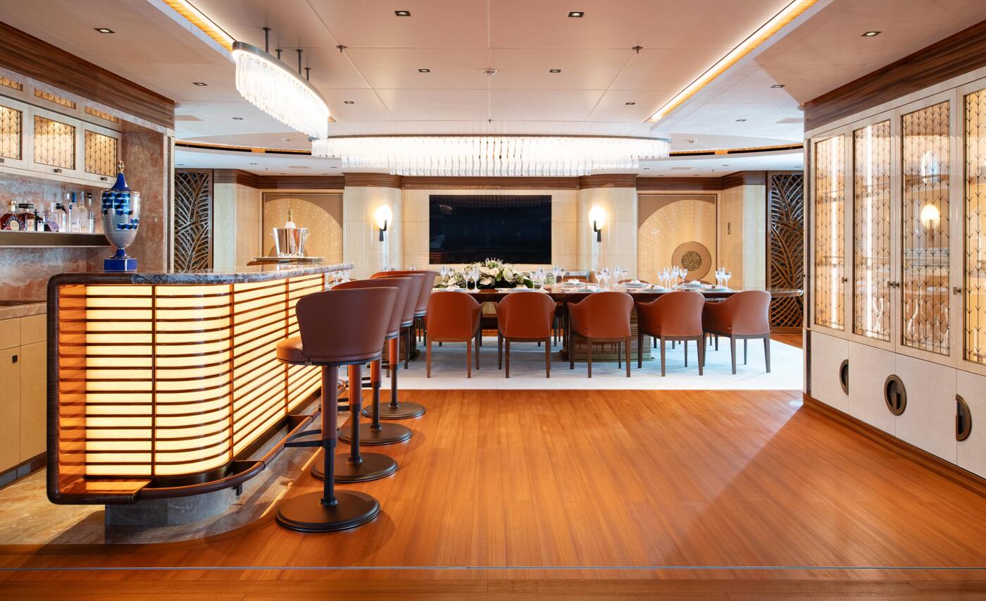 The main deck bar and formal dining table aboard ENERGY, lit by two long crystal chandeliers
