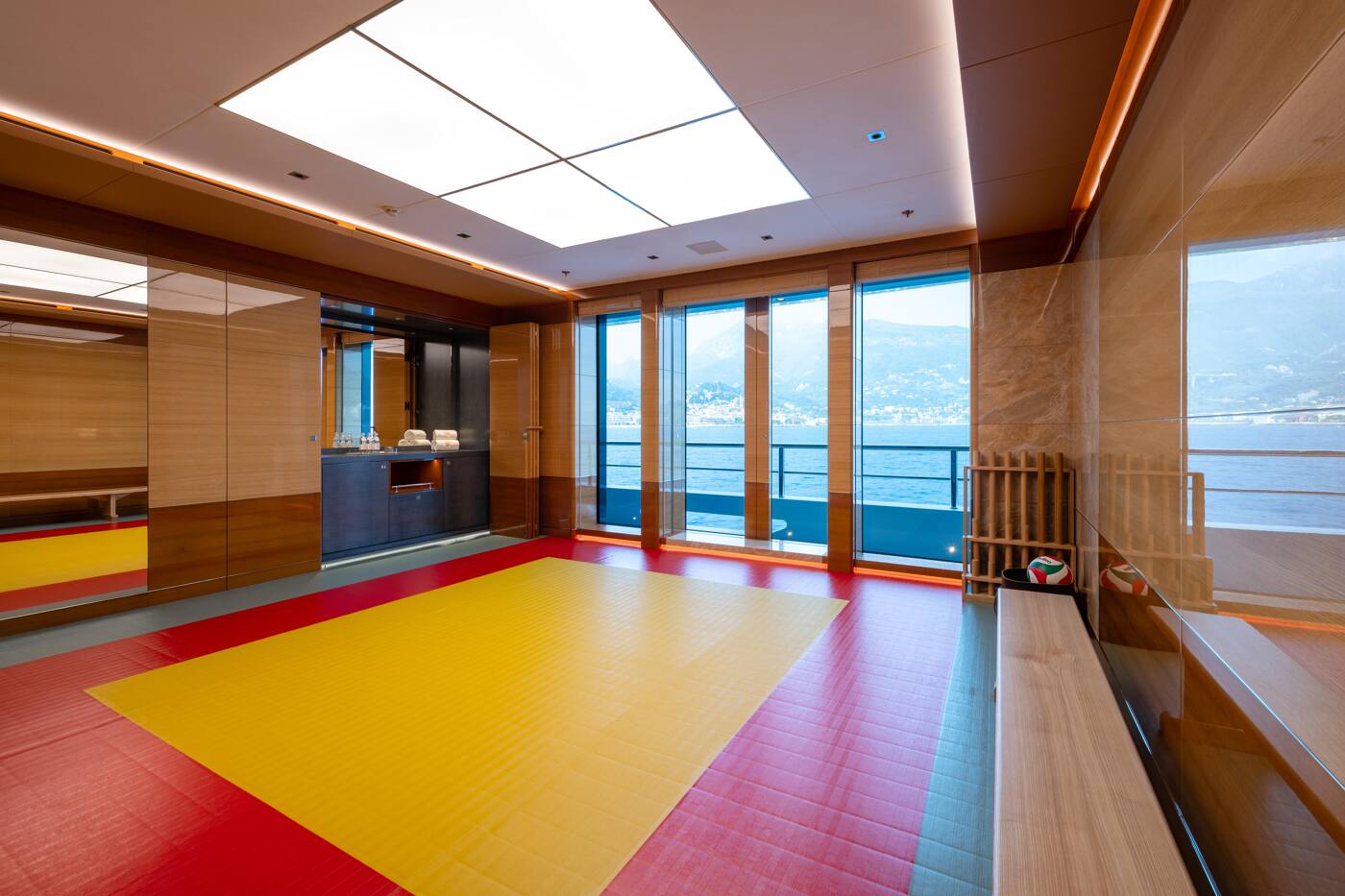 The martial arts room aboard ENERGY, matted in red and yellow with full-height windows onto the sea