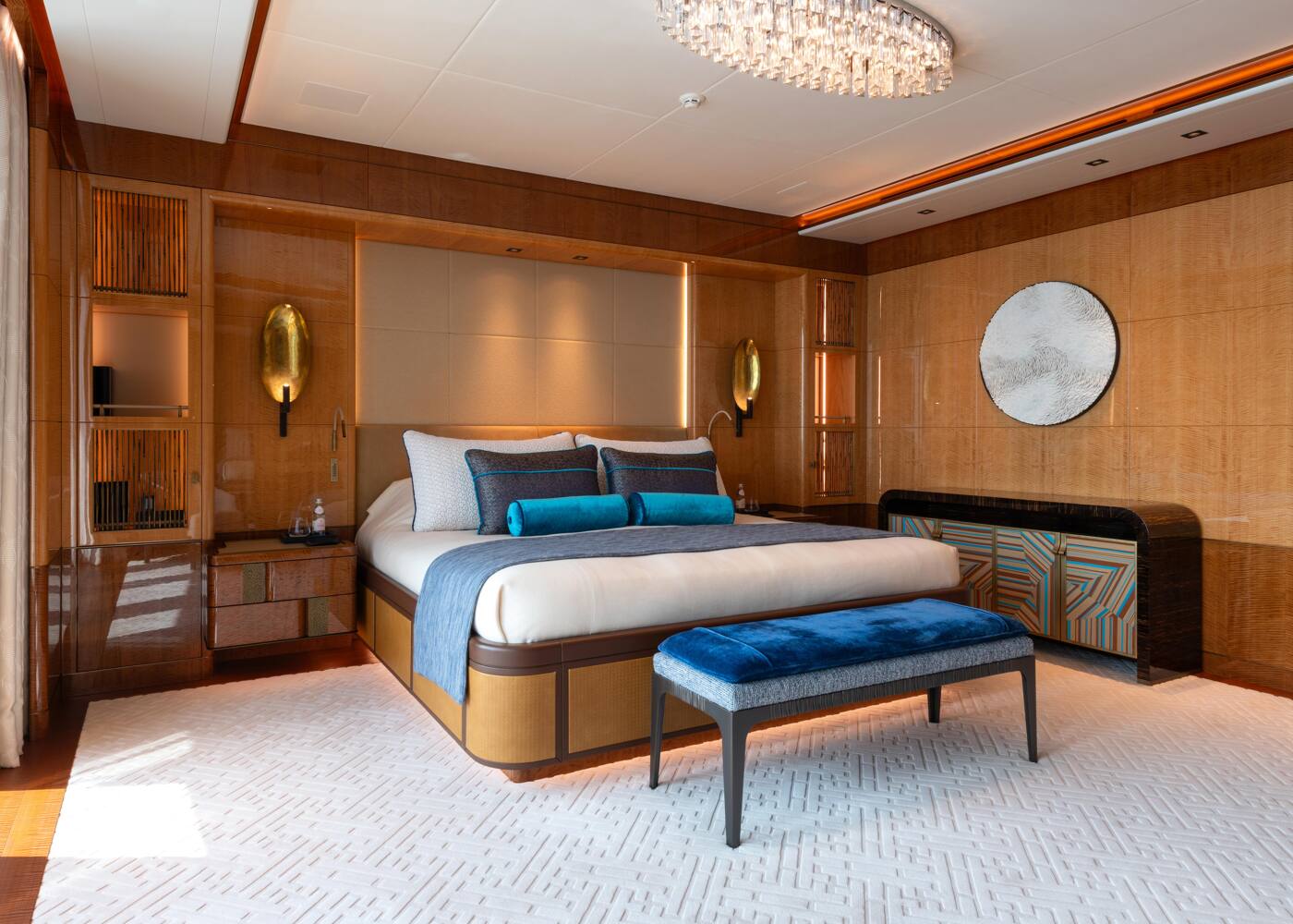 A guest suite aboard ENERGY, panelled in figured wood with a blue velvet bench at the foot of the bed