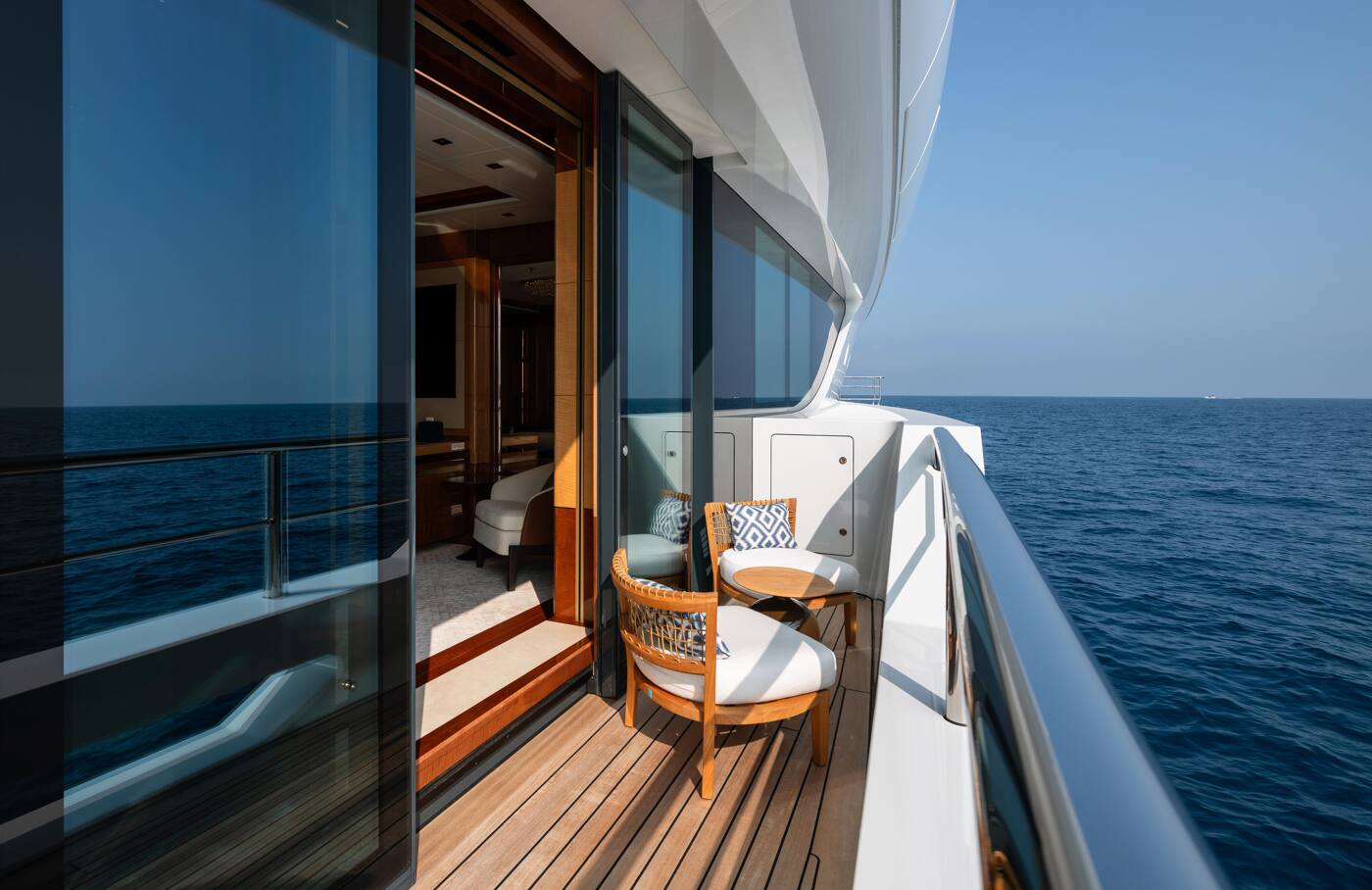 A private balcony off a guest suite aboard ENERGY, with two woven armchairs facing open water